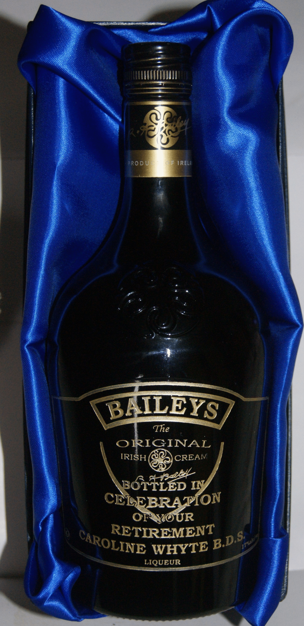 A bottle of Baileys engraved by sandblasting after which the engraving is filled with gold paint.