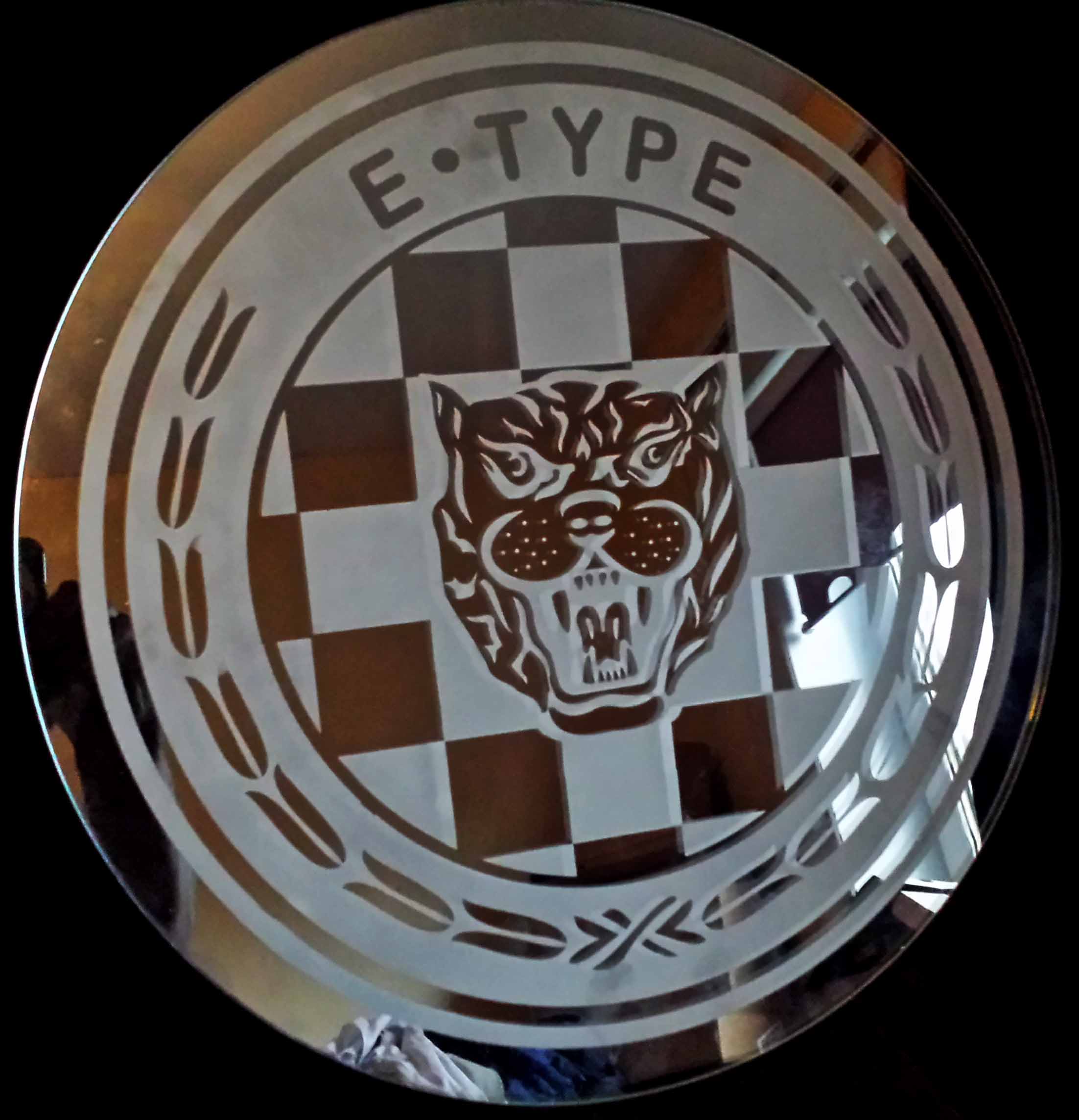 A round piece of safety glass 22 inch in diameter engraved with the E Type Jaguar logo.