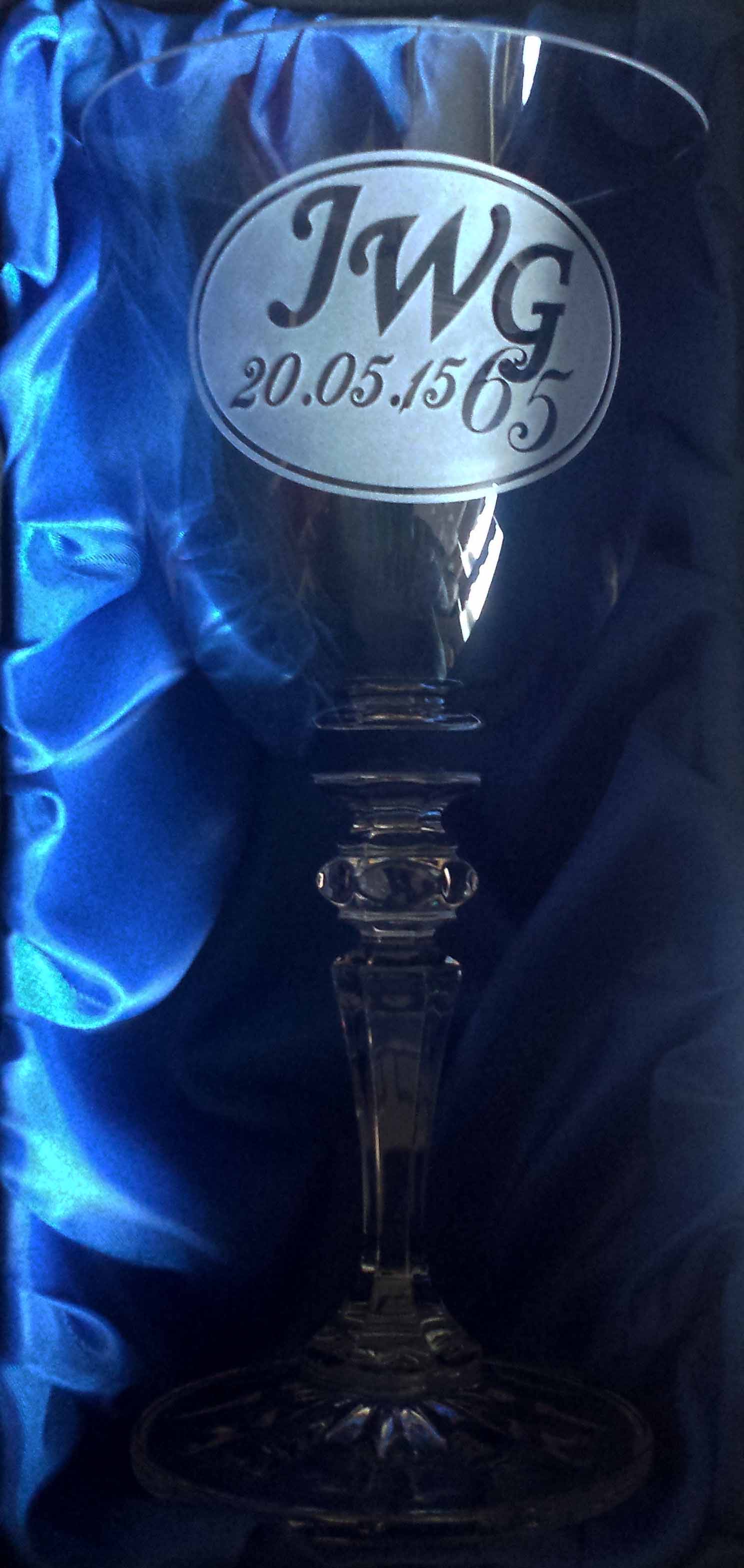 A crystal wine glass with the letters JWG and a date engraved in negative.