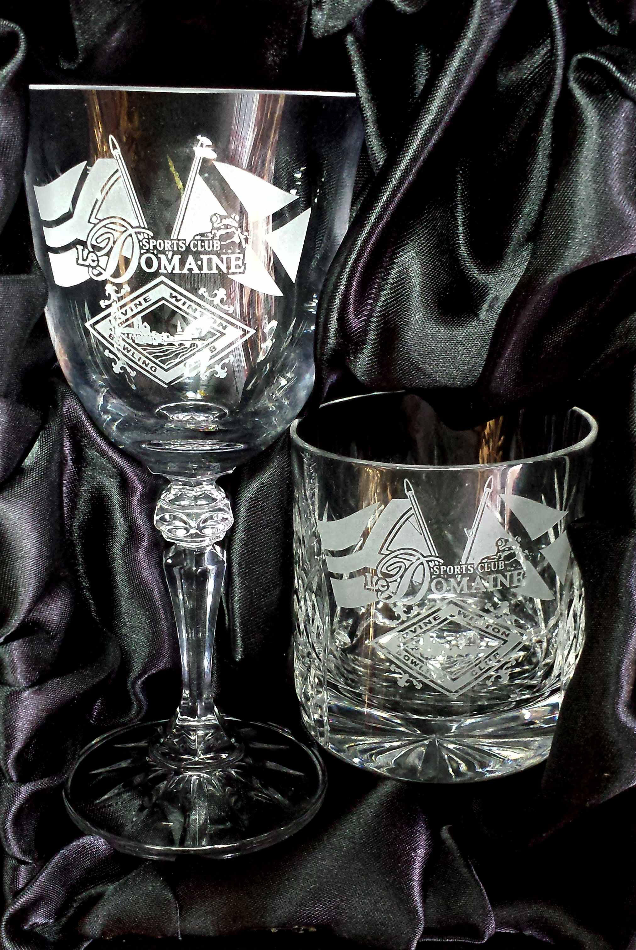 A Wine and a whisky glass engraved with the logo of LeDomaine Sports Club and Irvine Winton Bowling club plus the flags of Scotland and South Africa.